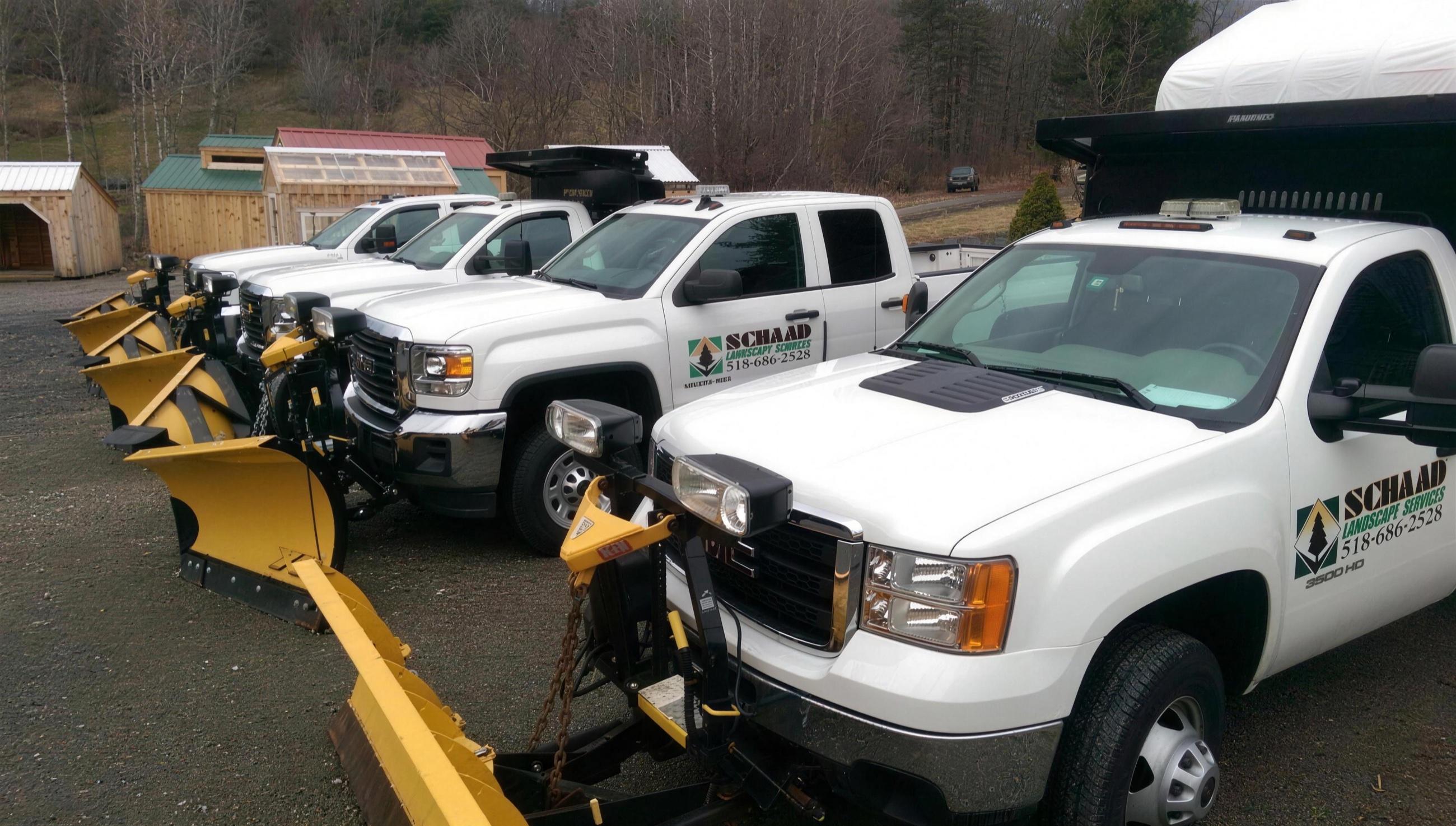 Schaad Landscape Services plow trucks angled in a row with yellow plow blades mounted, ready for snow removal